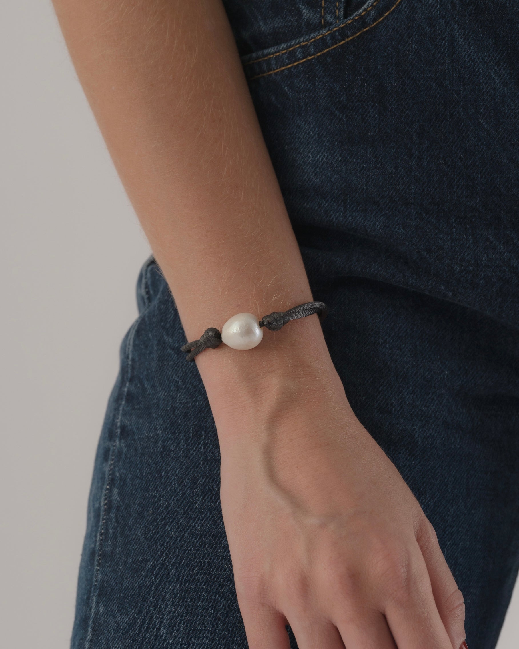 Pearl bracelet on a wrist with a neutral background