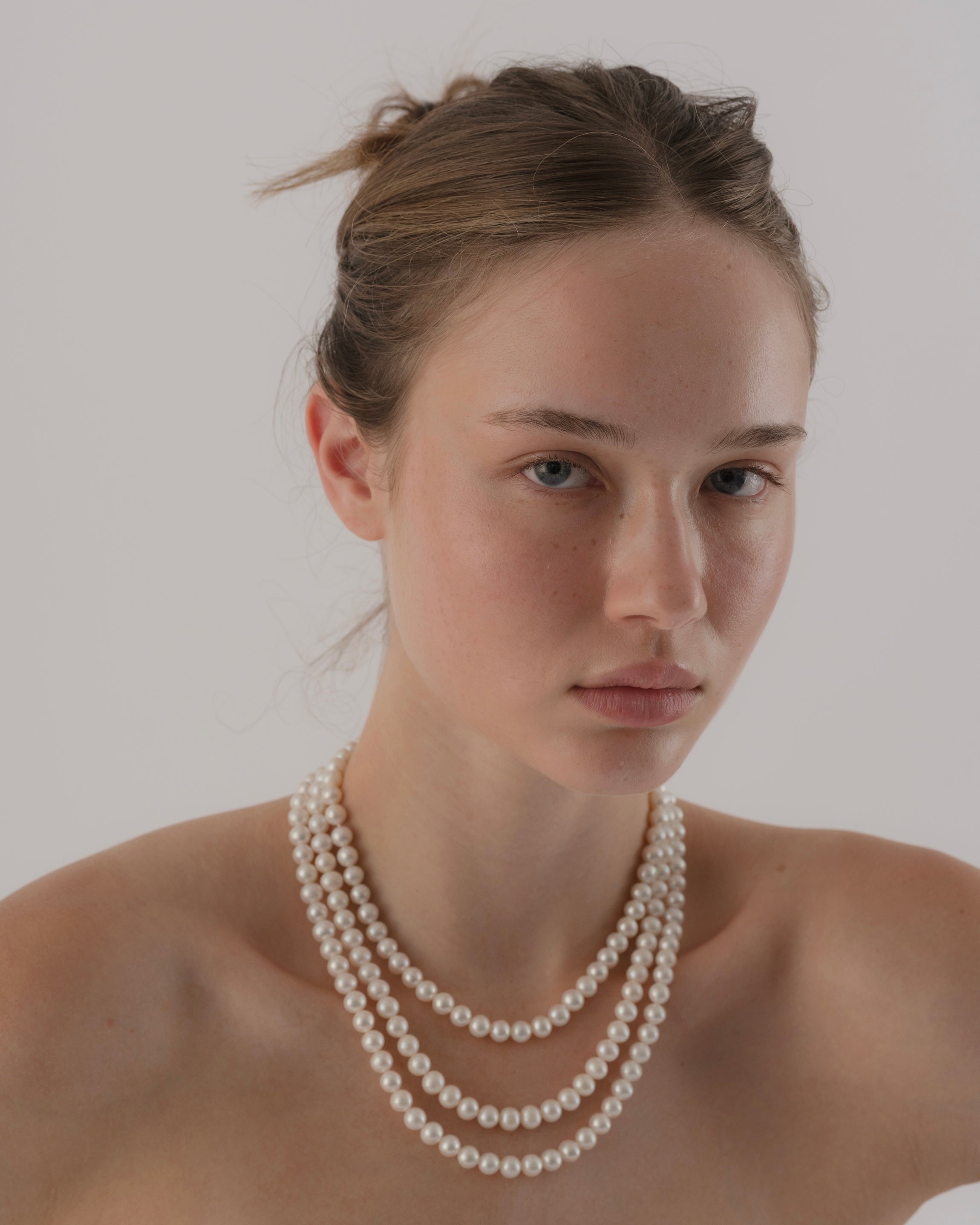 Woman wearing a pearl necklace against a plain background