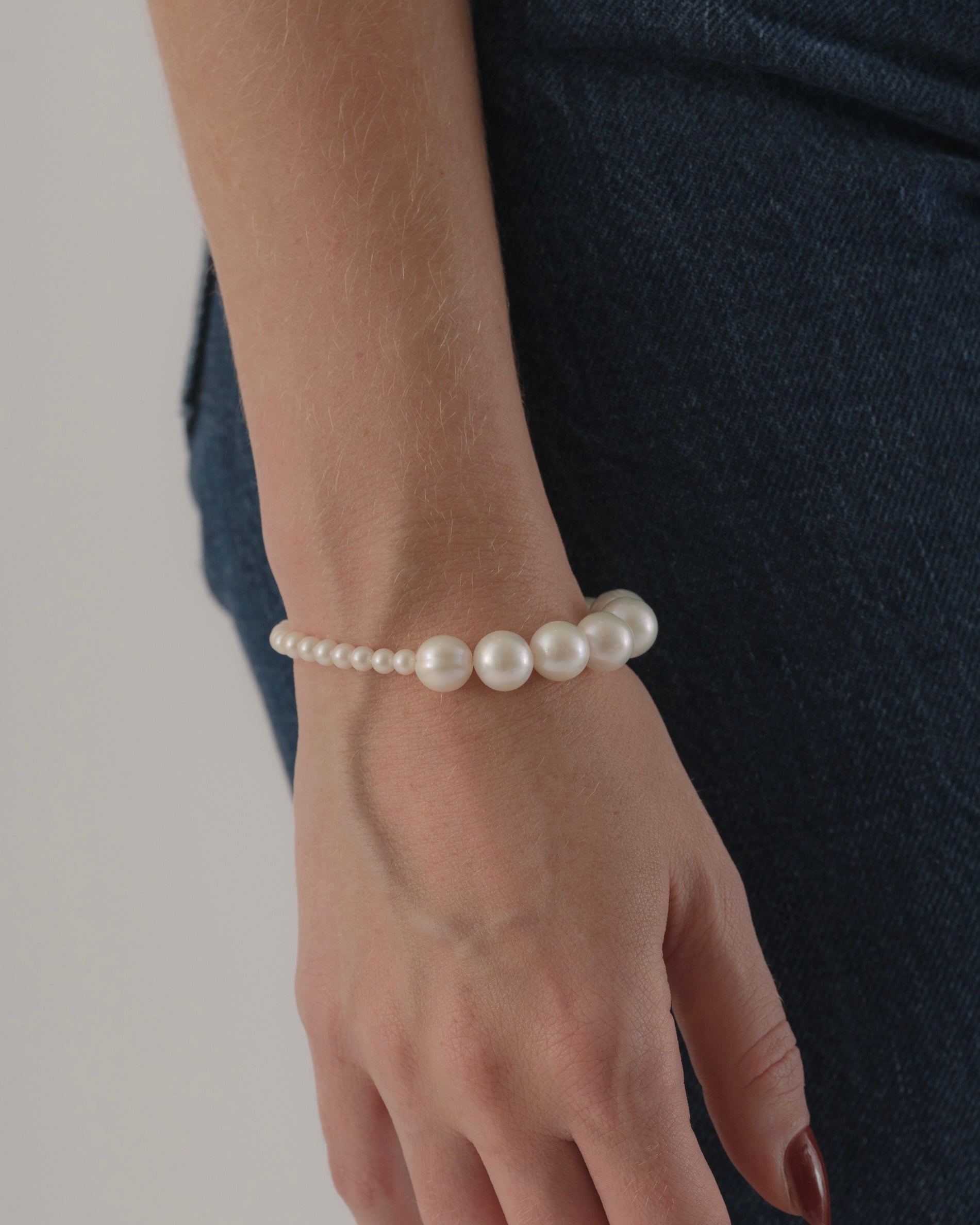 Pearl bracelet on a wrist with a neutral background