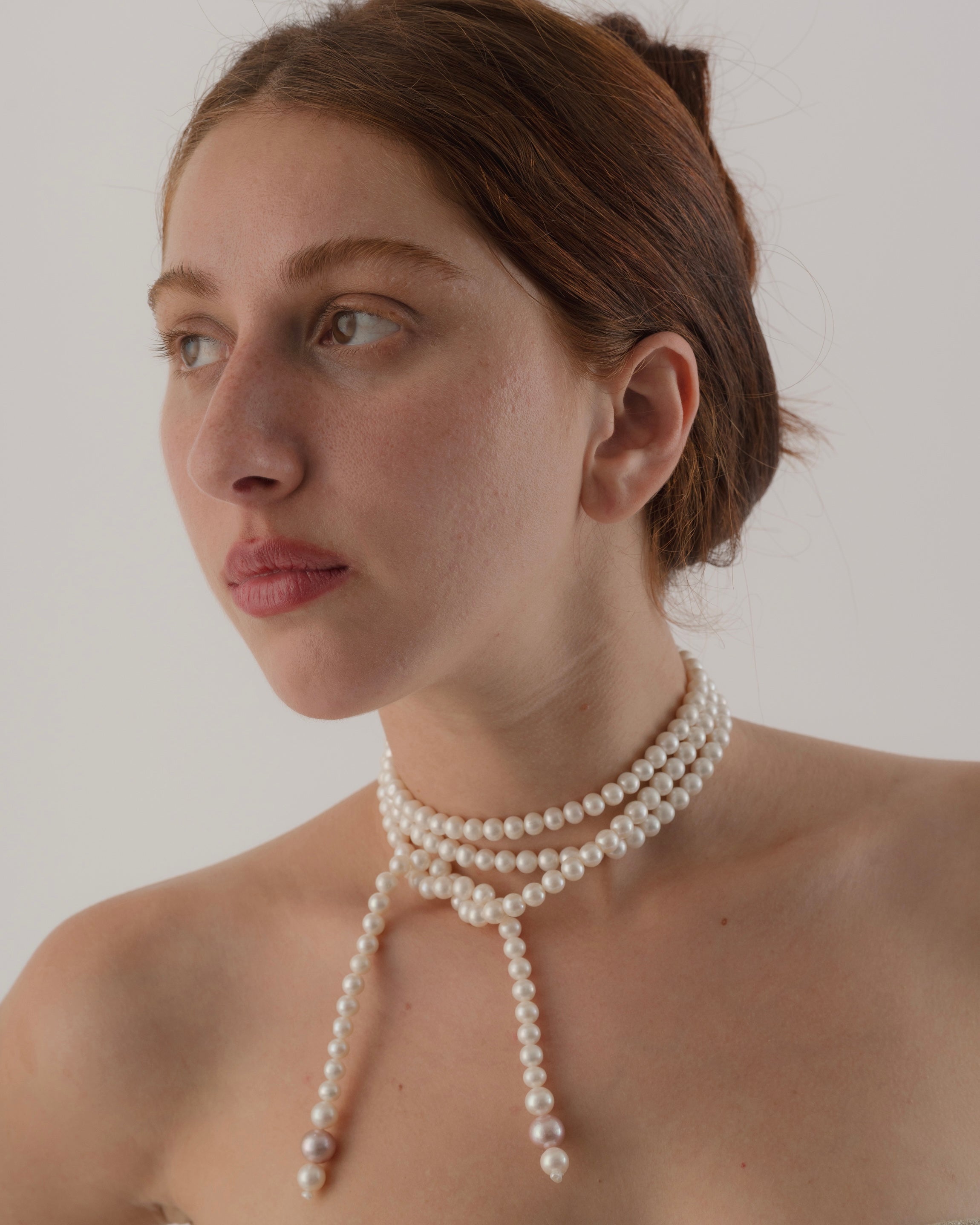 Woman wearing a pearl necklace against a plain background