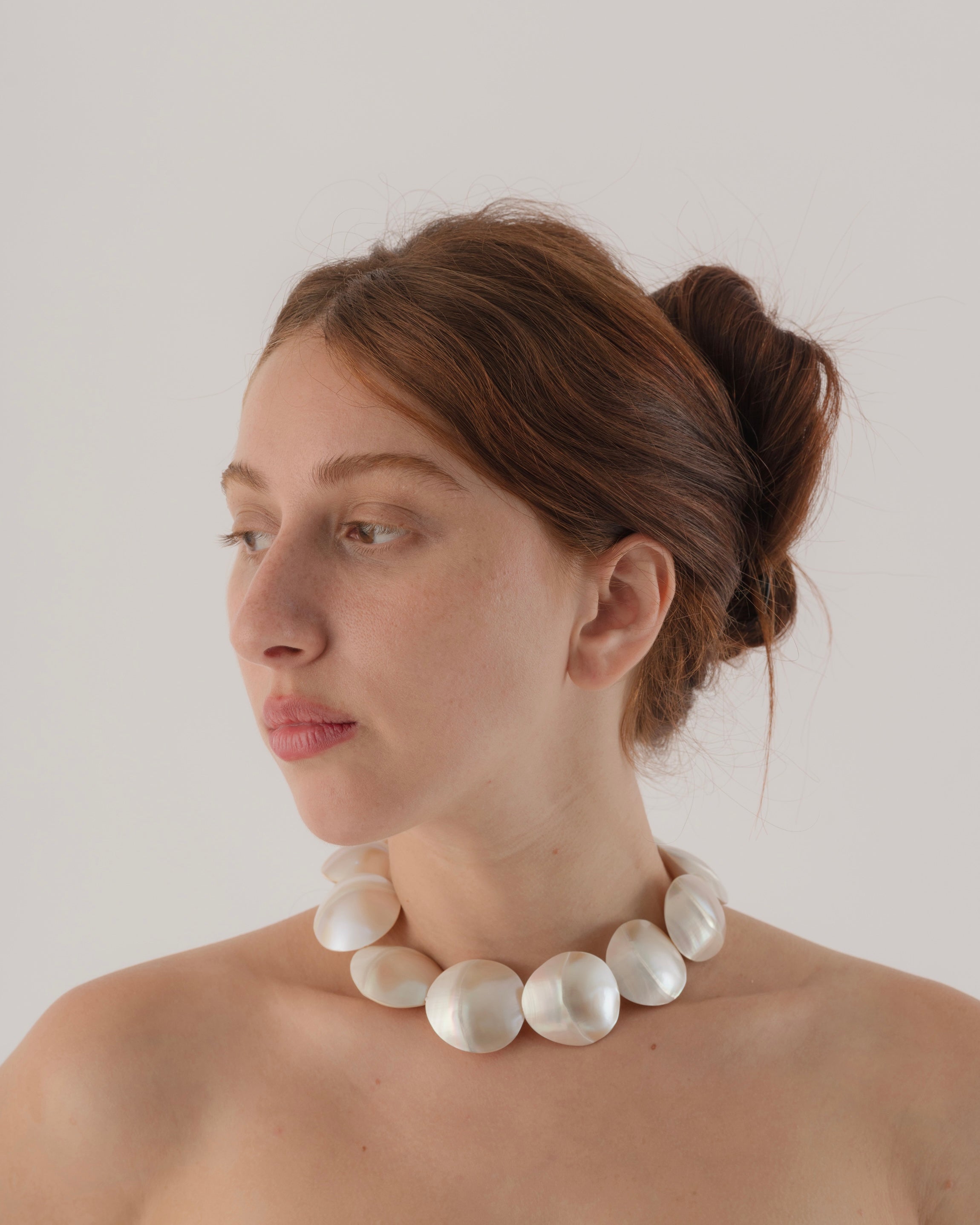 Woman wearing a pearl necklace against a plain background