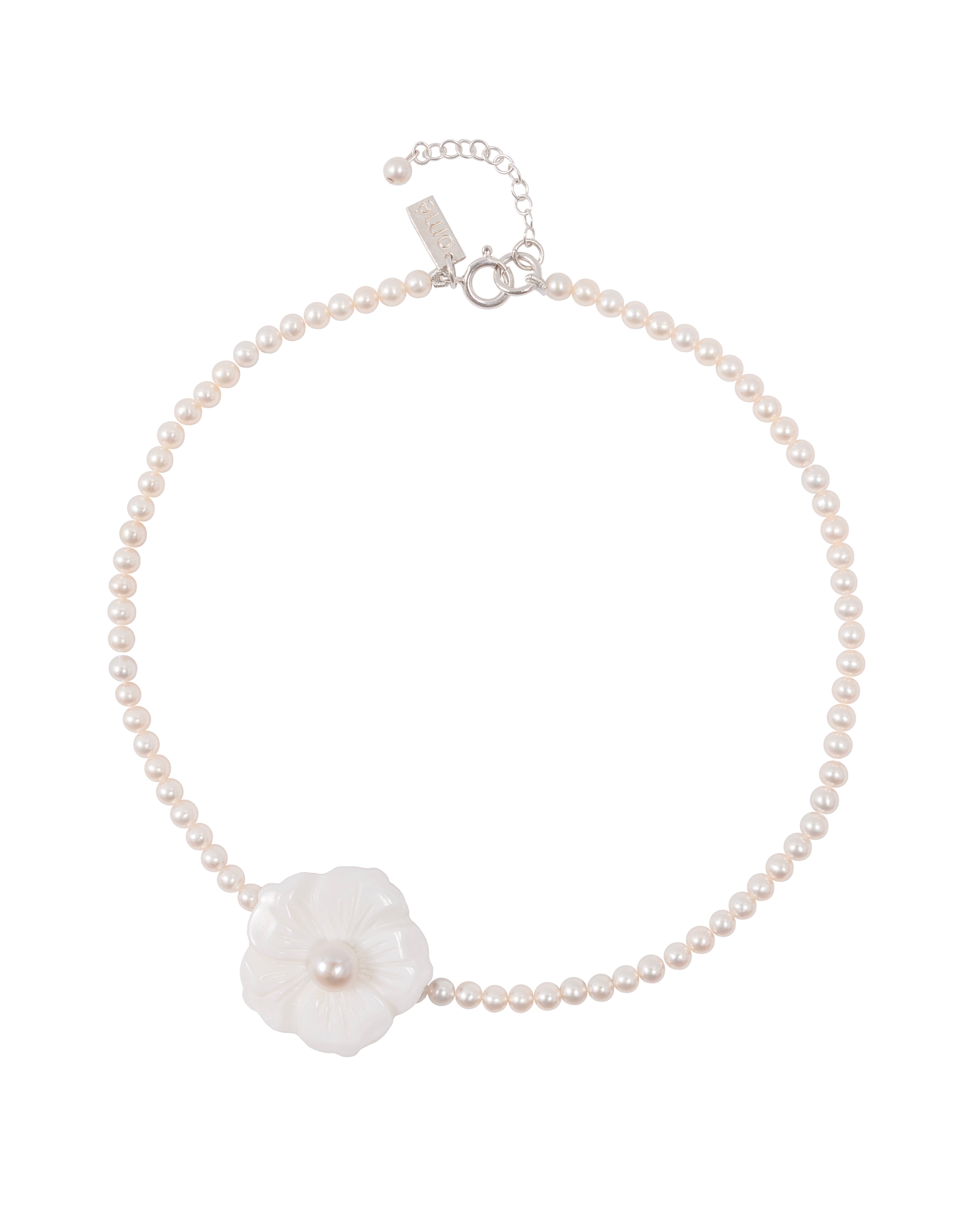 A necklace with freshwater pearls and a white Mother of Pearl flower charm positioned asymmetrically.