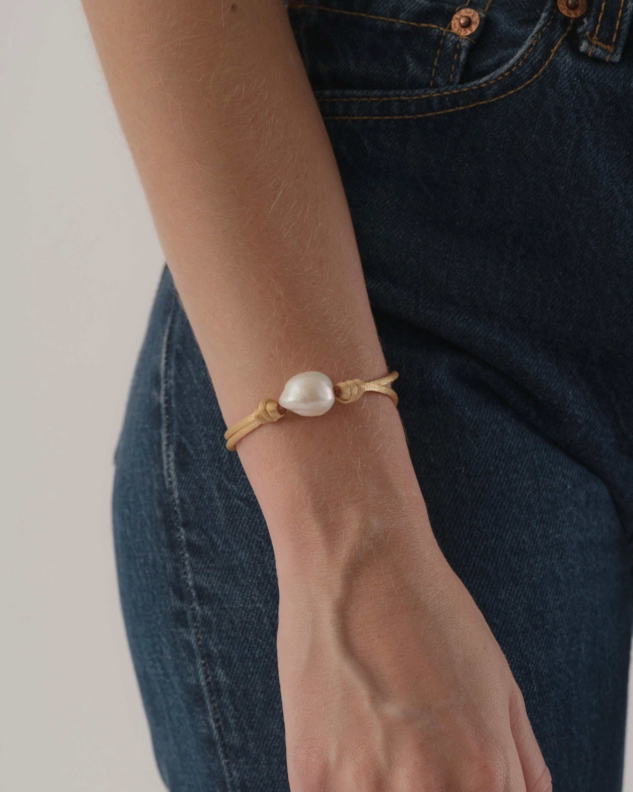 Pearl bracelet on a wrist with a neutral background