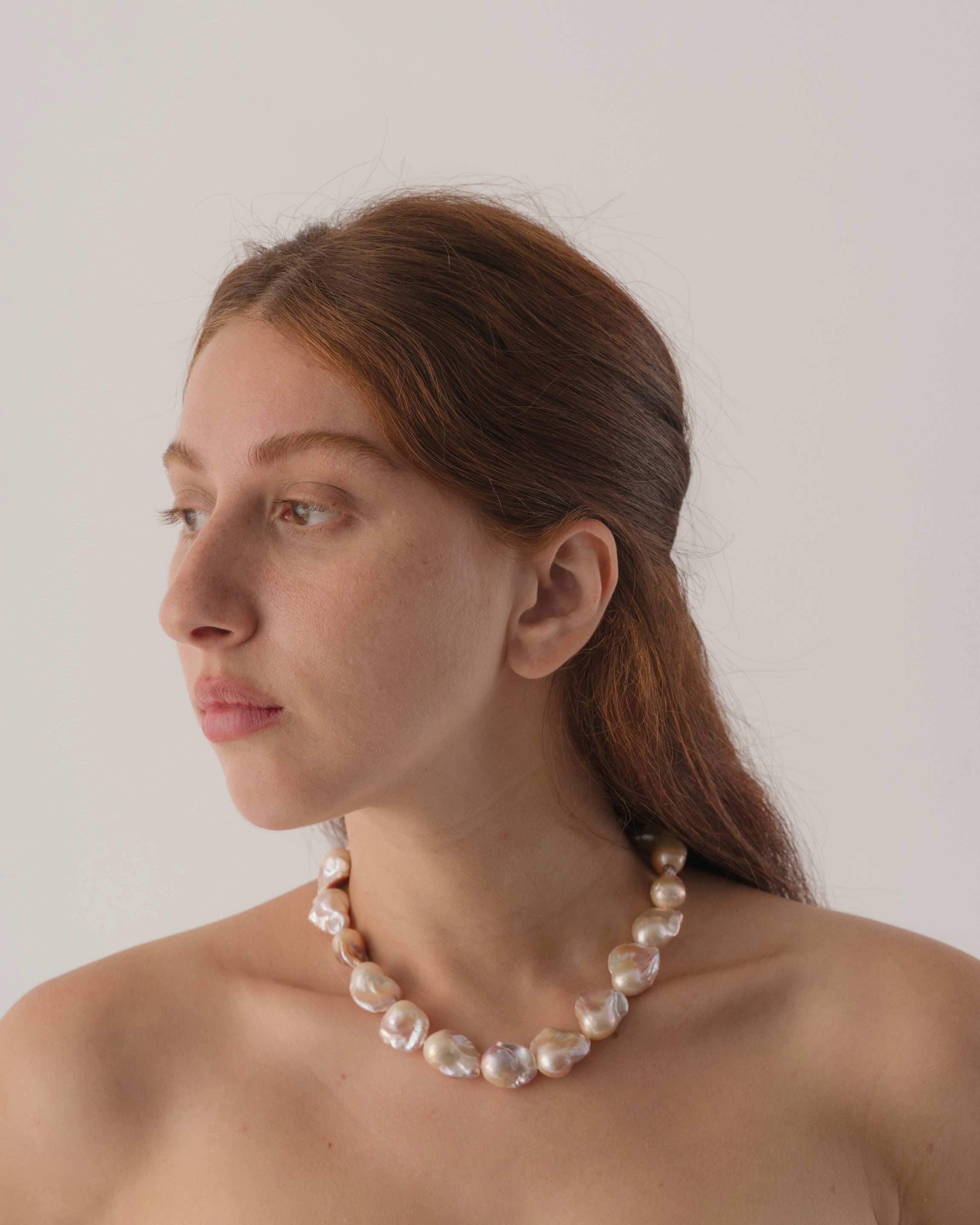 Woman wearing a pearl necklace against a plain background