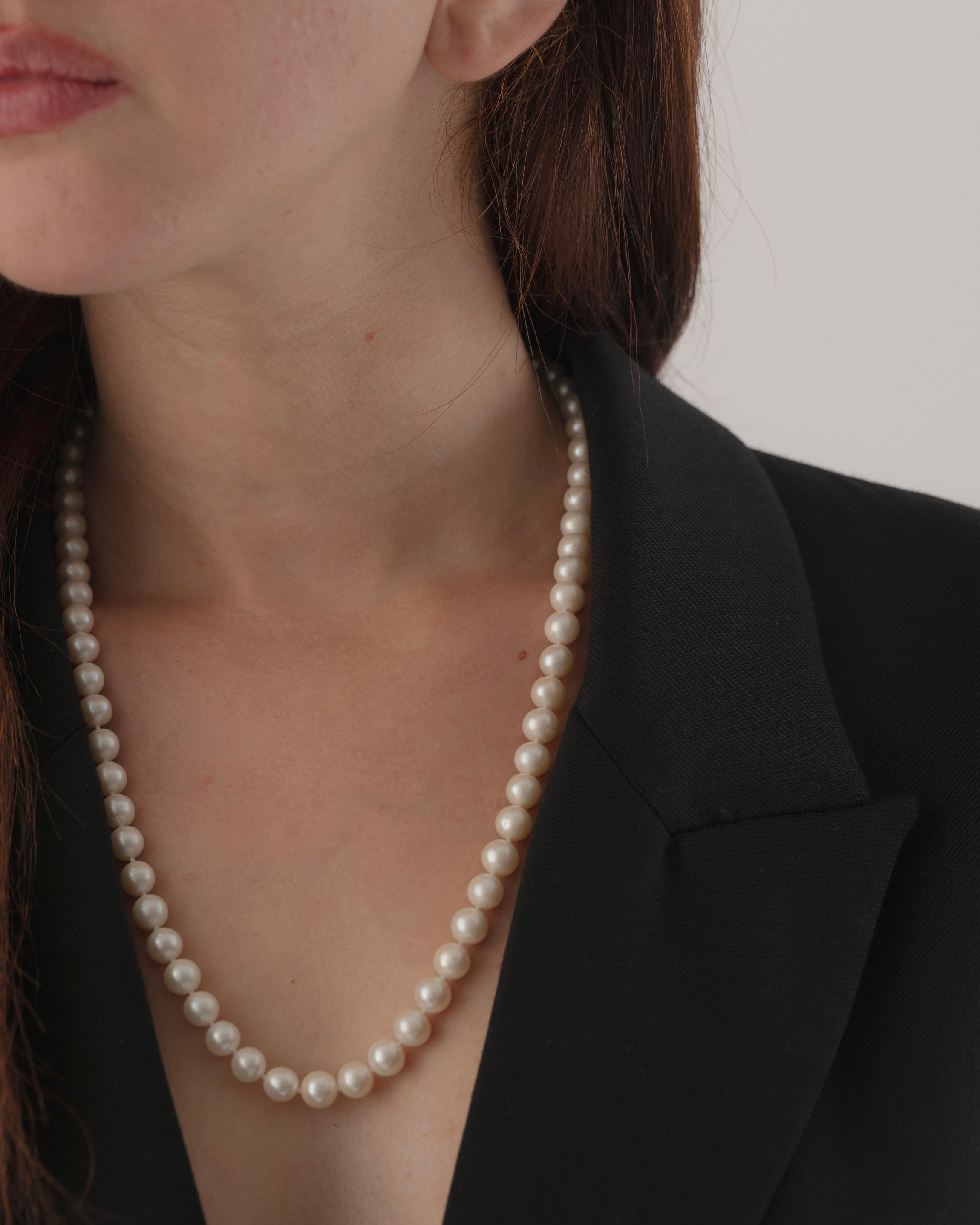 Pearl necklace worn by a person against a neutral background