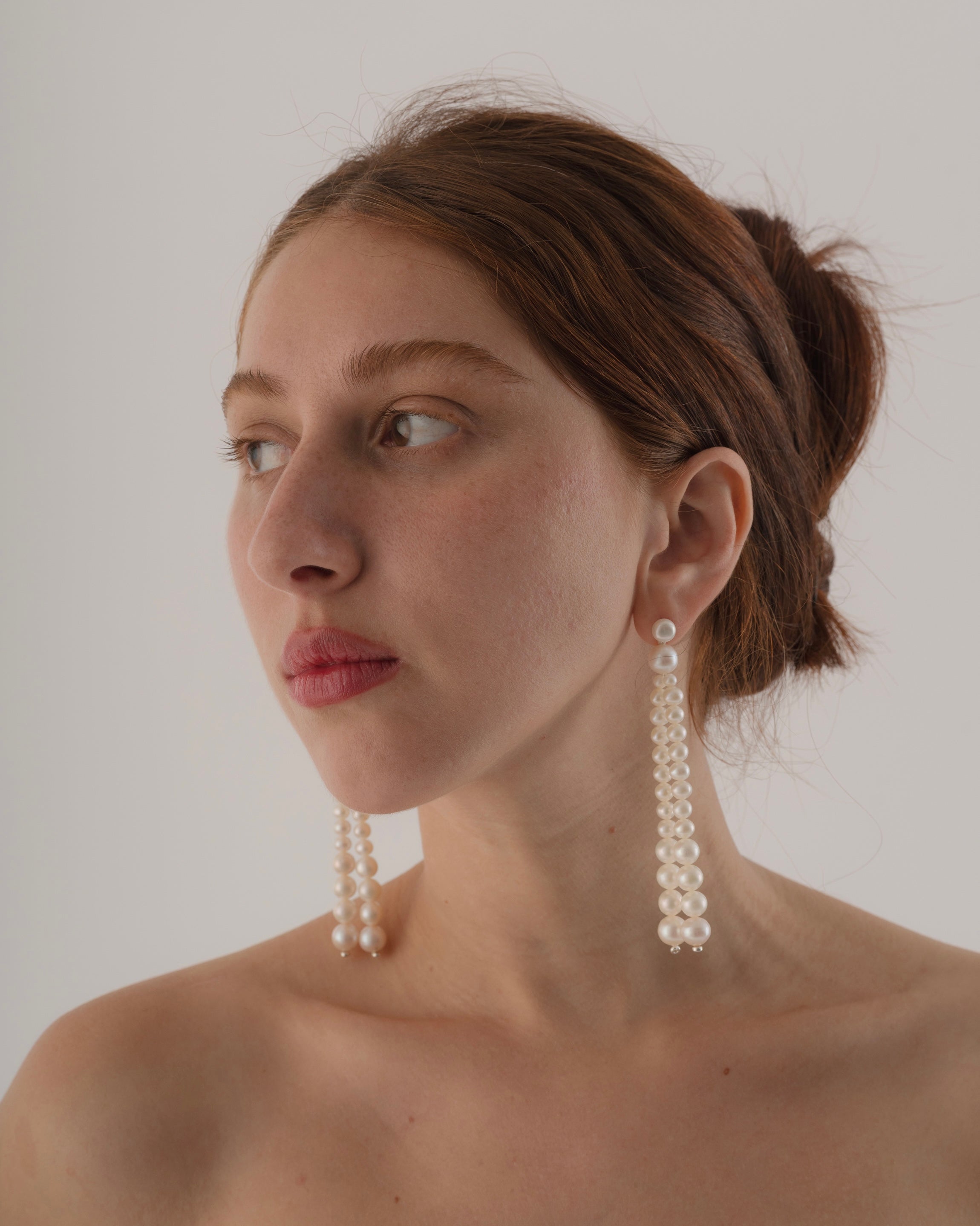 Woman wearing pearl earrings against a plain background