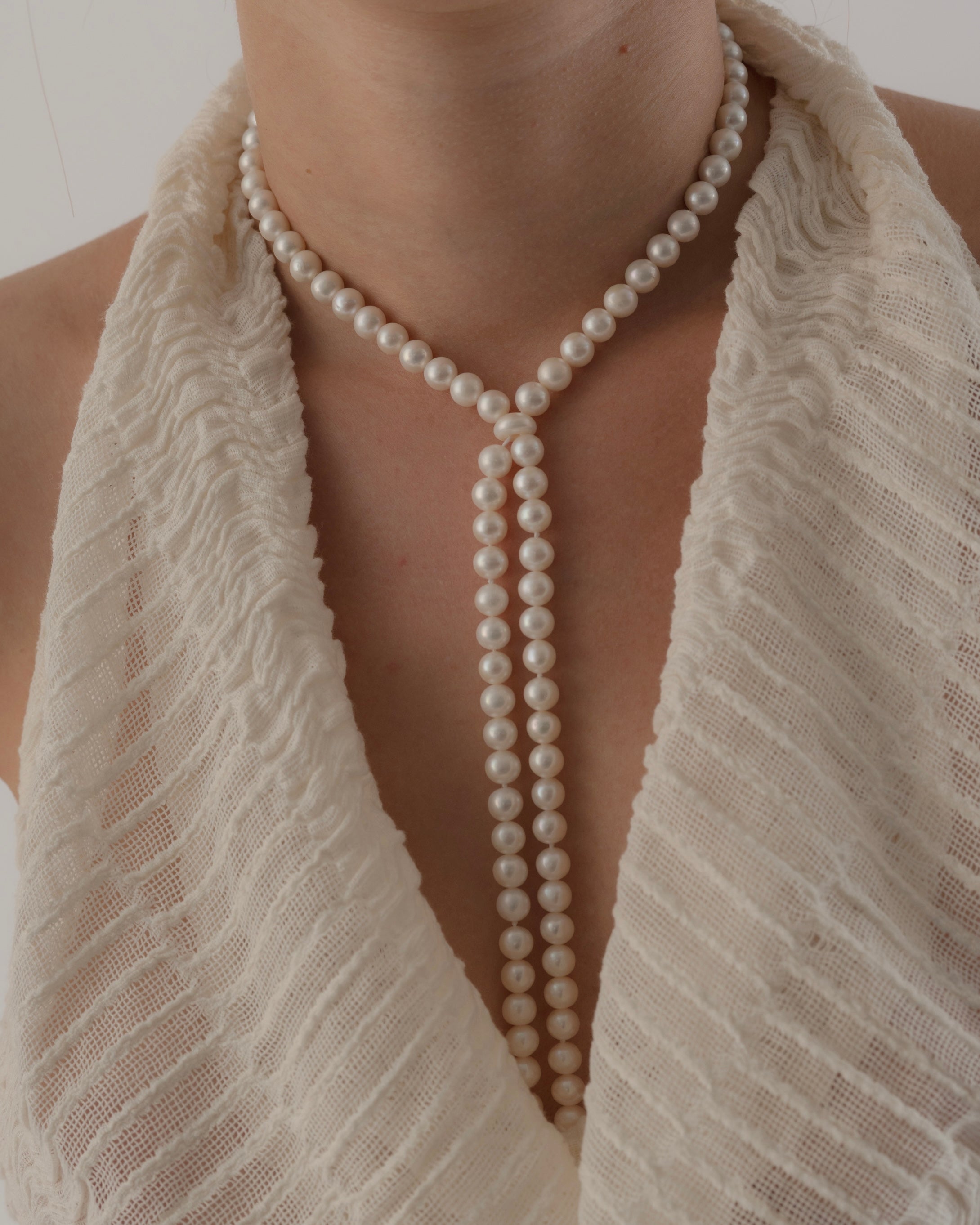 Pearl necklace draped over a textured white garment