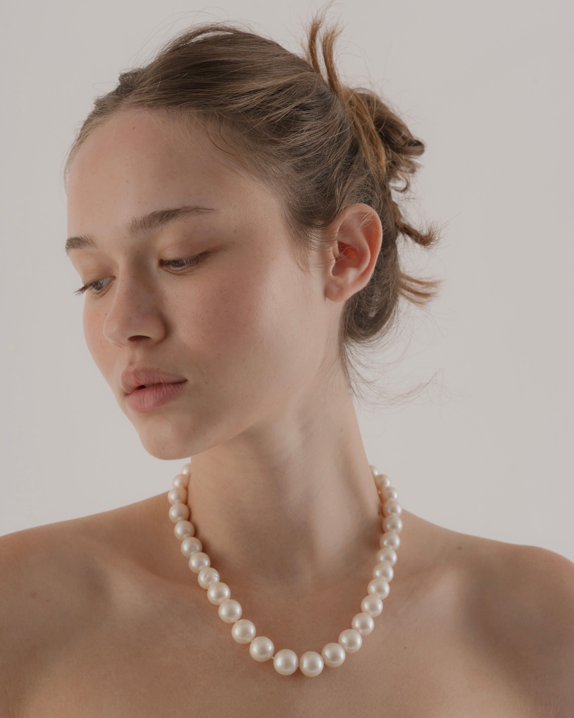 Woman wearing a pearl necklace against a plain background