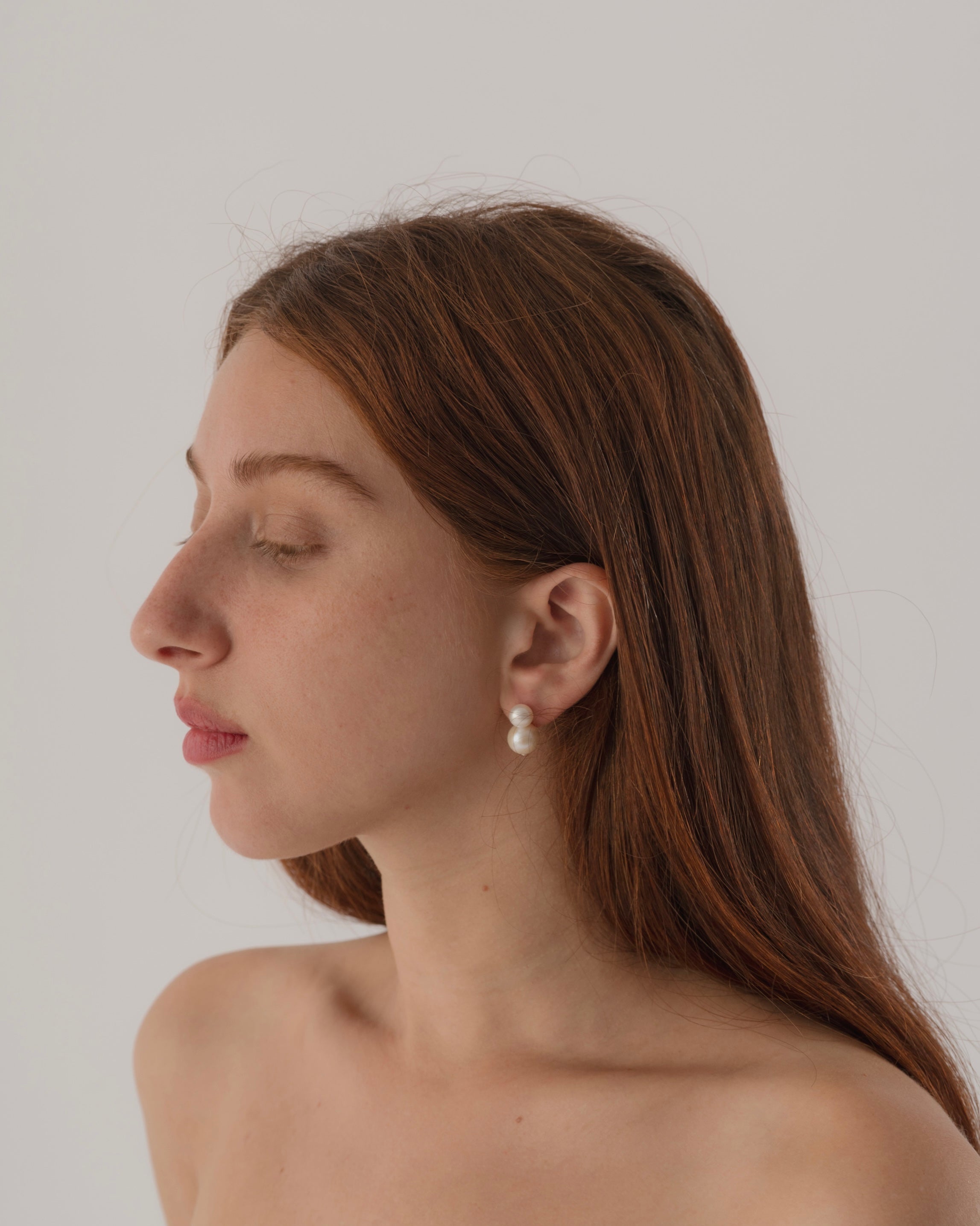 Woman wearing pearl earrings against a plain background
